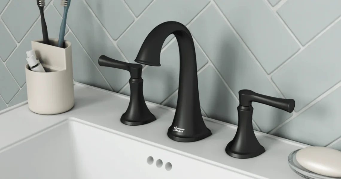 A modern bathroom sink with a matte black faucet and handles, a white soap dish holding a bar of soap, and a toothbrush holder with two toothbrushes, all set against a light blue tile wall.